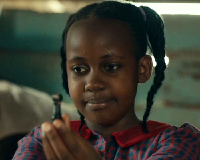 Young child actor holding a small object, reflecting a somber moment.