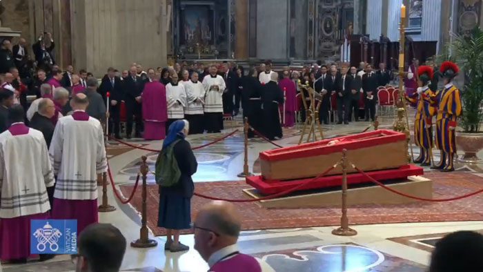 Nun breaks protocol mourning over the Pope's casket in a crowded cathedral setting.