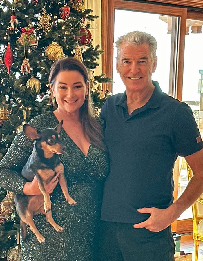 A couple smiling by a Christmas tree with a dog, celebrating stunning weight loss in festive attire. A couple smiling by a Christmas tree with a dog, celebrating stunning weight loss in festive attire.