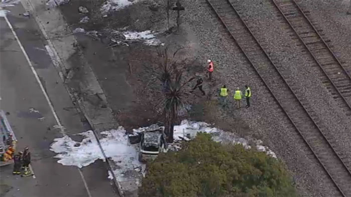Aerial view of a plane crash site near railroad tracks in Florida, with emergency responders assessing damage.