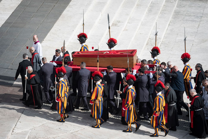 Pope Francis' open casket carried by guards in Vatican ceremony featuring Swiss Guards.