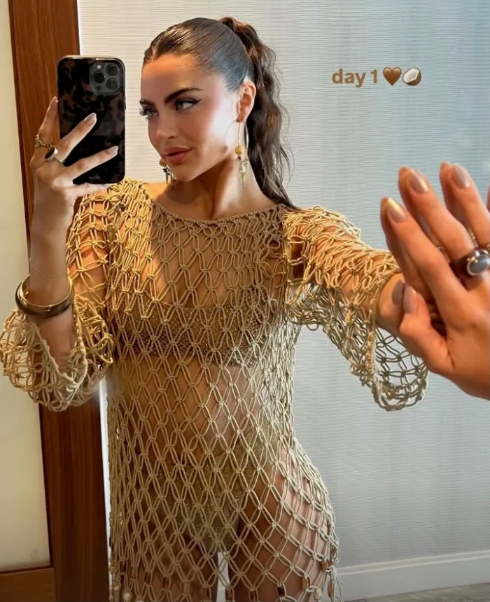Celebrity at Coachella 2025, wearing a netted outfit, capturing a mirror selfie.