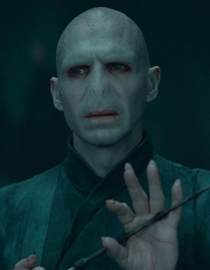 Bald character with pale skin, intense gaze, holding a wand, from a fantasy film scene. Bald character with pale skin, intense gaze, holding a wand, from a fantasy film scene.