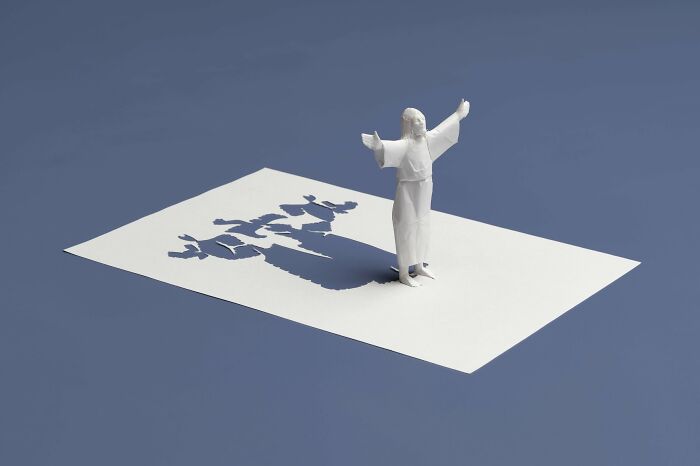 Paper mini world sculpture by Peter Callesen, featuring a figure with arms outstretched on a cut-out sheet.