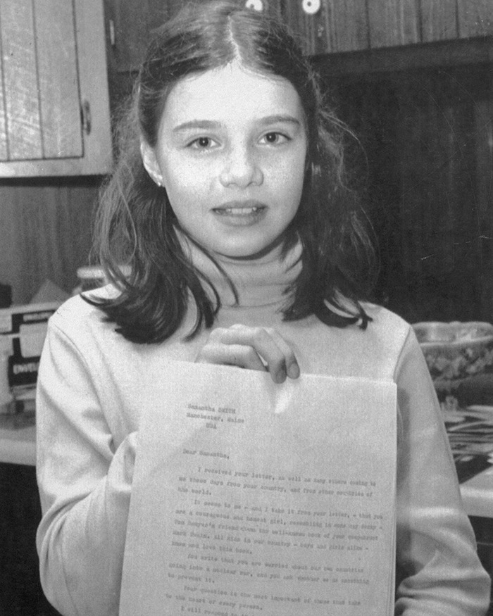 Young child actor holding a letter in a kitchen setting.
