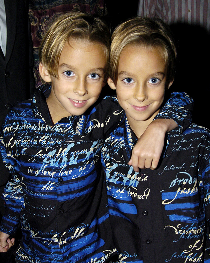 Two young child actors in matching blue patterned shirts, smiling and posing together closely.