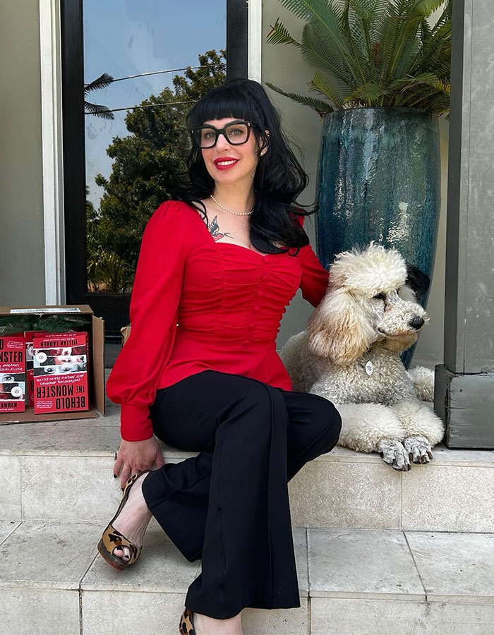 Woman in red top sitting with a poodle, books by her side, conveying a personal moment related to a legal situation.