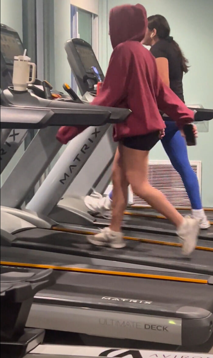 Two people running on treadmills, one in a red hoodie, demonstrating lack of self-awareness at the gym.