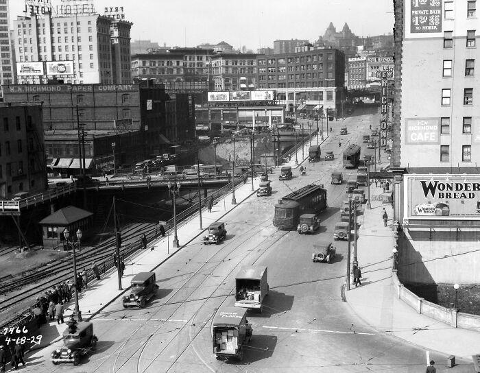 Busy American city street from 100 years ago showing vintage cars, streetcars, and pedestrians in daily life.
