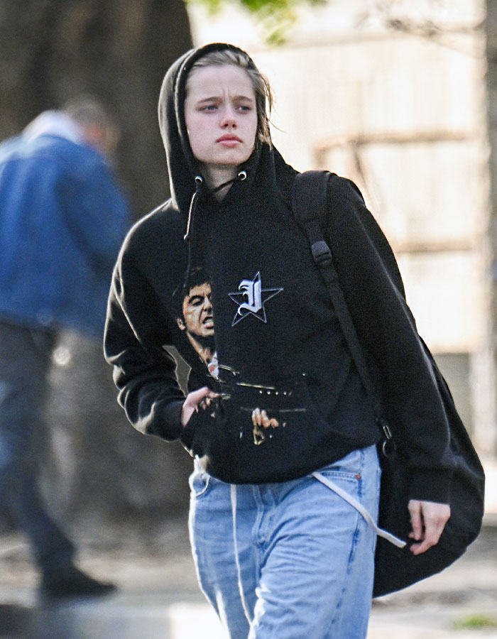 Twisted transition: person in casual attire, wearing a black hoodie and jeans, walking outdoors with a backpack. Twisted transition: person in casual attire, wearing a black hoodie and jeans, walking outdoors with a backpack.
