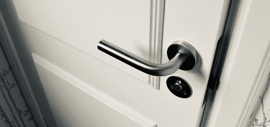 A closed white door with a modern silver handle, symbolizing ethical dilemmas and choices.