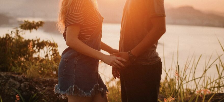 Couple holding hands at sunset, symbolizing ethical dilemmas in relationships.