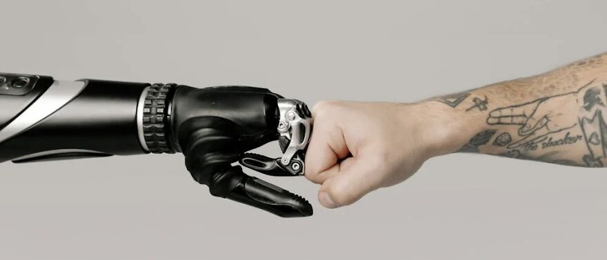 A human fist bumping a robotic hand, highlighting ethical dilemmas in technology.