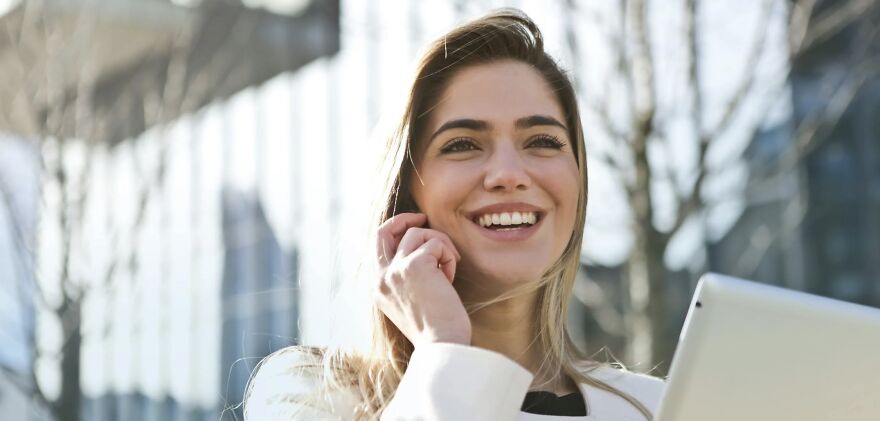 Smiling woman with tablet outdoors, representing ethical dilemmas and decision-making concepts.