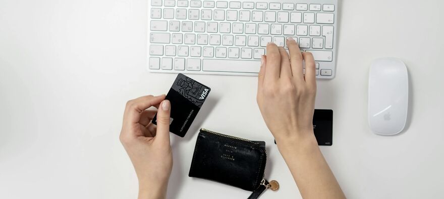 Hands holding a credit card over a keyboard, illustrating troubling ethical dilemmas in financial decisions.