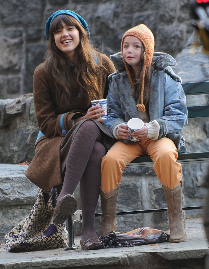 Two women on a bench in winter clothing, smiling and holding coffee cups, related to child star's mysterious passing.