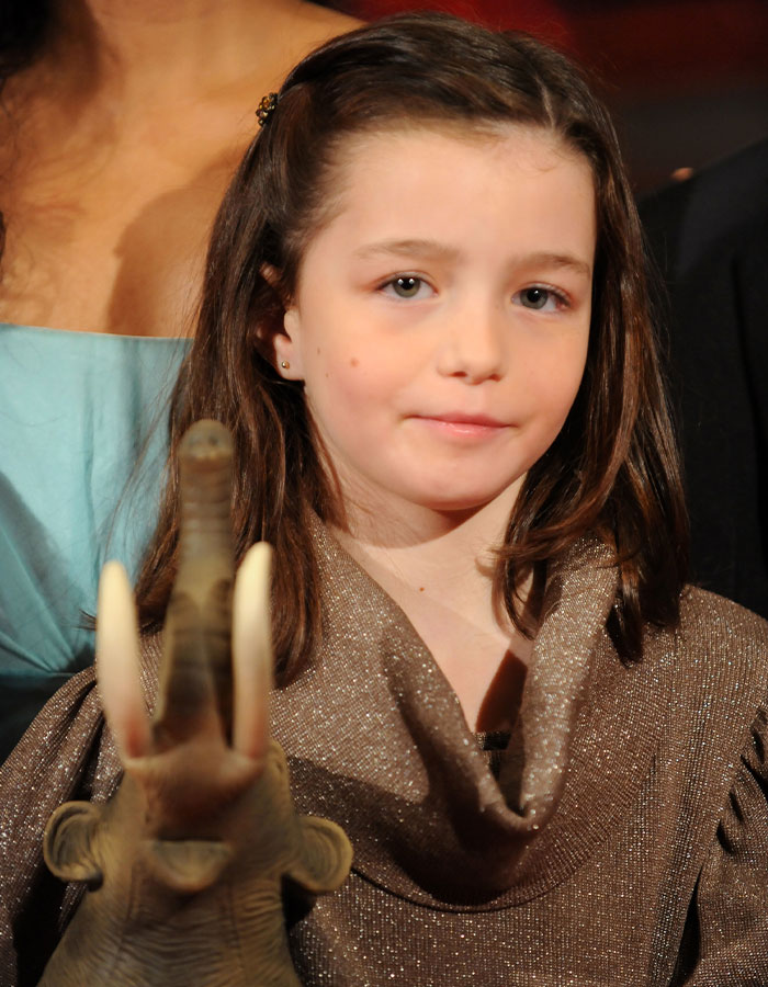 A former child star poses in a silver dress, holding a toy elephant, highlighting mystery of pregnancy revelation.