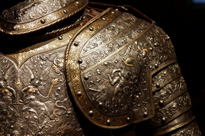Ornately engraved armor showcasing historical artifacts with intricate designs and figures.