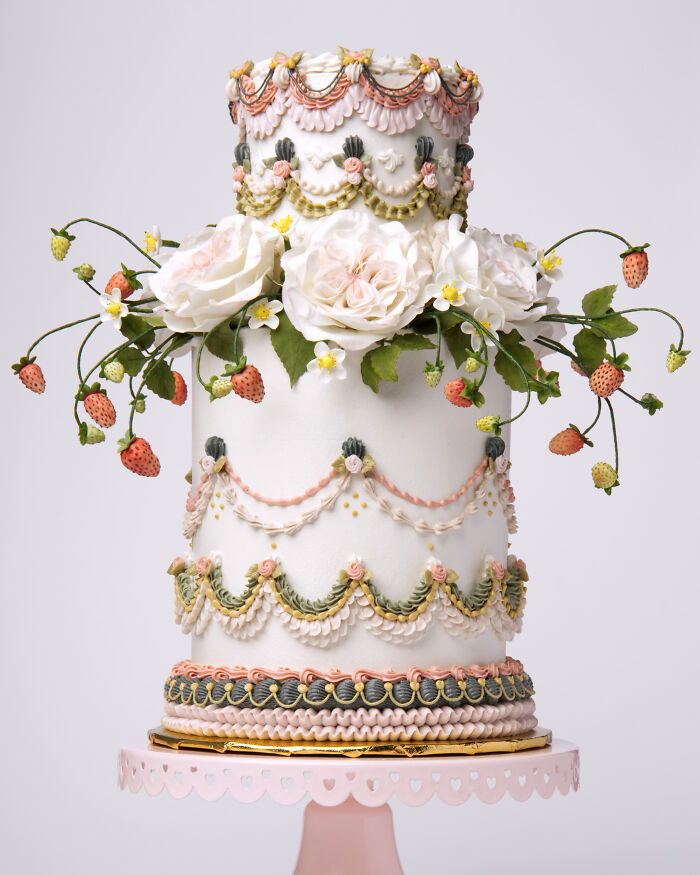 Vegan cake adorned with sculpted roses and strawberries, featuring intricate decorative details.
