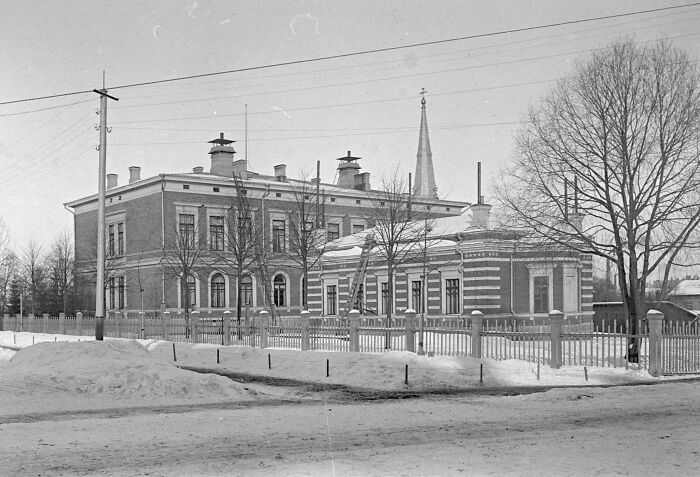 Historic European building in winter with snow-covered ground and bare trees, illustrating life in Europe 100 years ago.