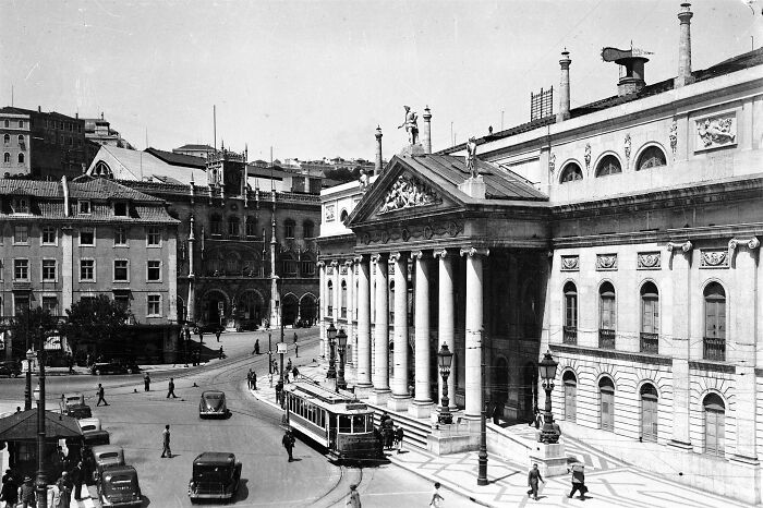 Historic European city street with vintage cars and a tram, showing life in Europe 100 years ago.