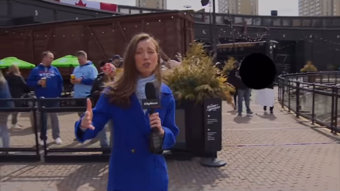 TV reporter in blue coat holding a microphone in an outdoor setting, surrounded by people, discussing misogynistic comments.