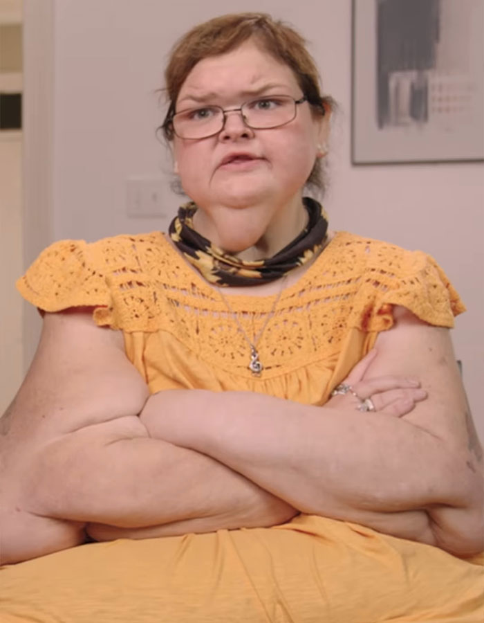Woman in yellow dress with arms crossed, talking about 500-pound transformation from 1000-Lb Sisters.