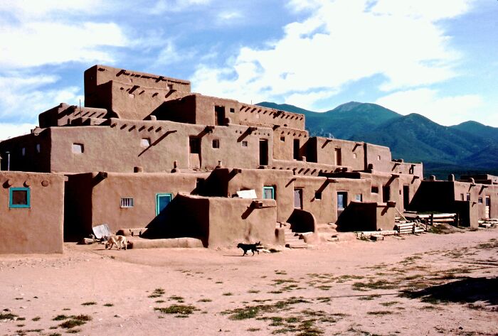 Adobe structures against mountain backdrop, exemplifying lesser-known architectural wonders.