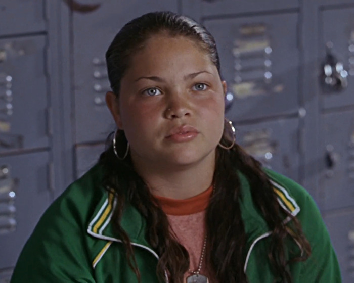 Young actor in a scene set against a backdrop of grey school lockers.