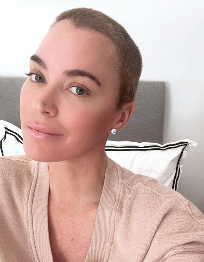 Woman in a beige sweater with short hair, smiling softly, symbolizing hope during a cancer battle.