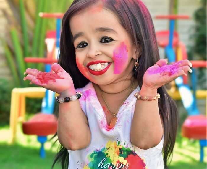 Child smiling with colorful face paint, enjoying a playful moment outdoors.