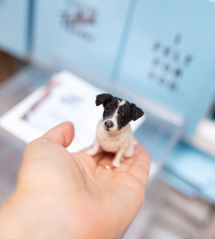 Hand holding a cute felted version of a small dog, showcasing a detailed pet creation.