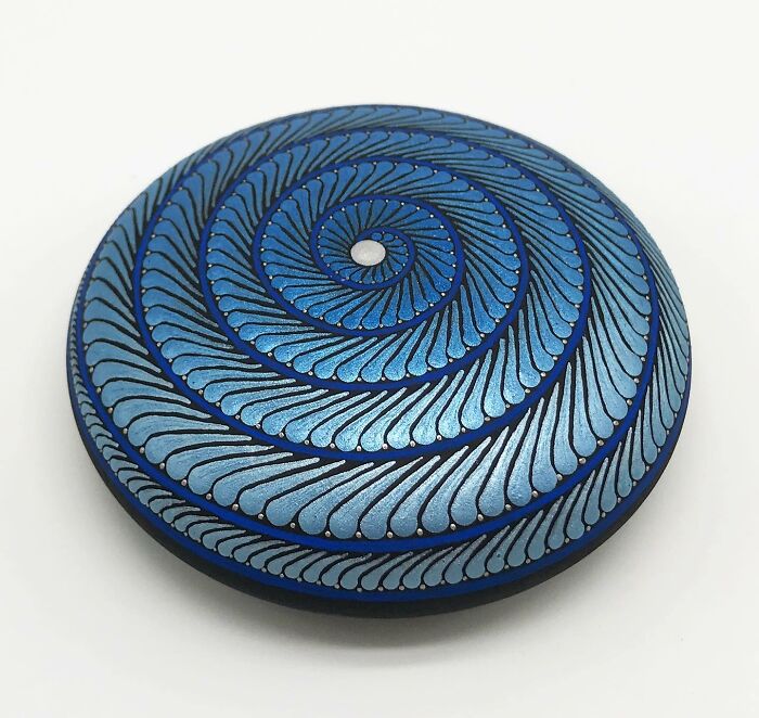 Blue mandala design on a stone with swirling patterns, showcasing beautiful artwork.