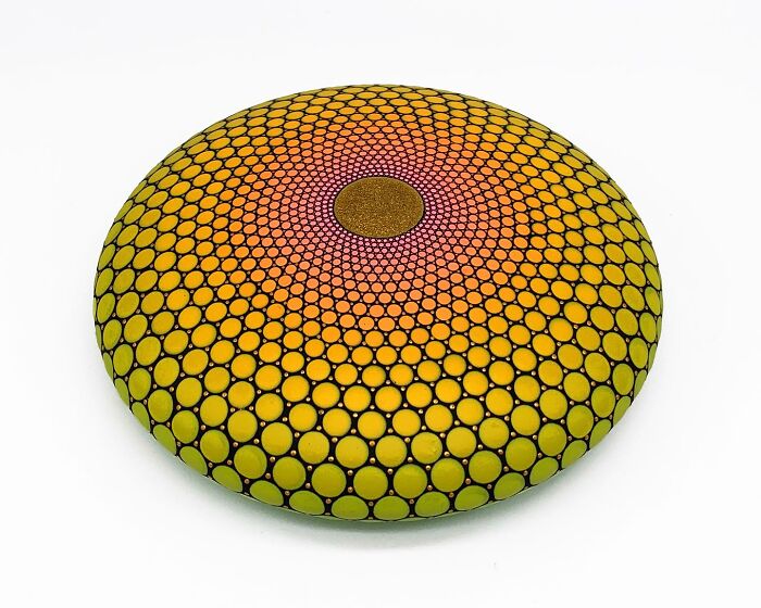 Colorful mandala design painted on a round stone with intricate patterns.