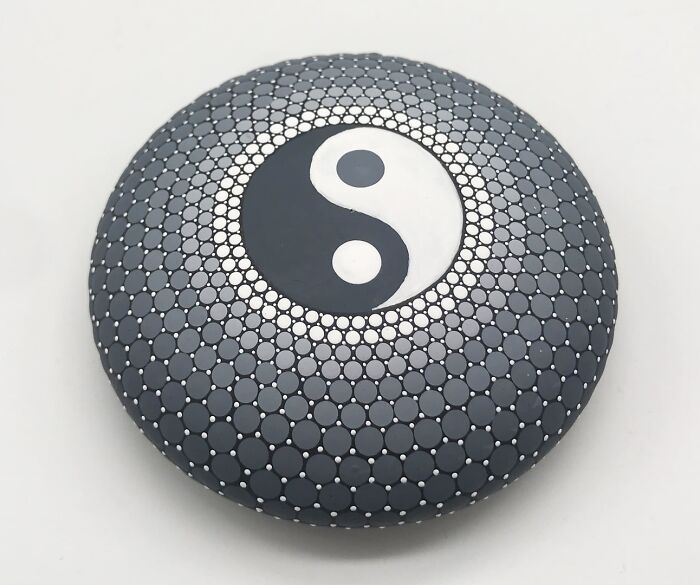 Stone painted with a mesmerizingly beautiful yin-yang mandala design.