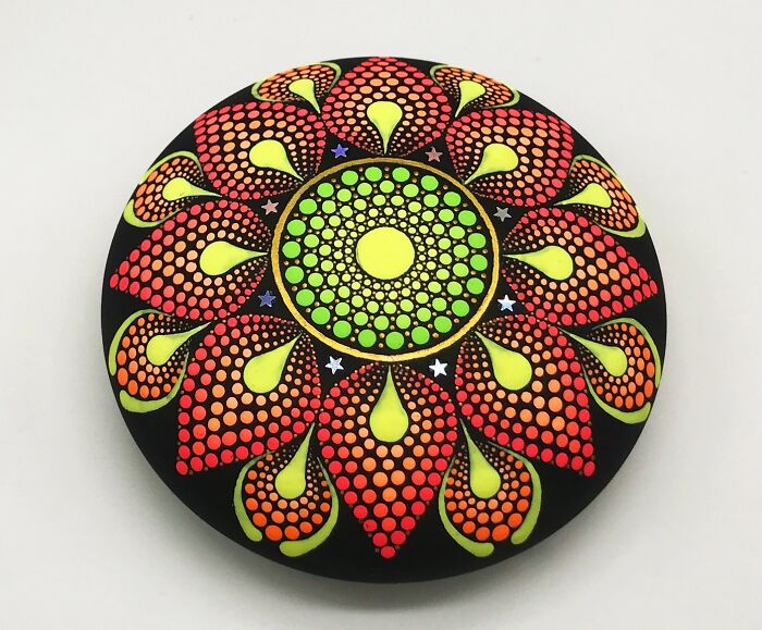 Colorful mandala painted on a stone with vibrant dots and intricate patterns.