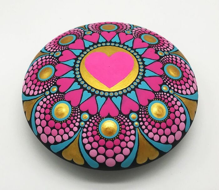 Beautiful mandala art on stone featuring vibrant pink, blue, and gold patterns with a central heart design.