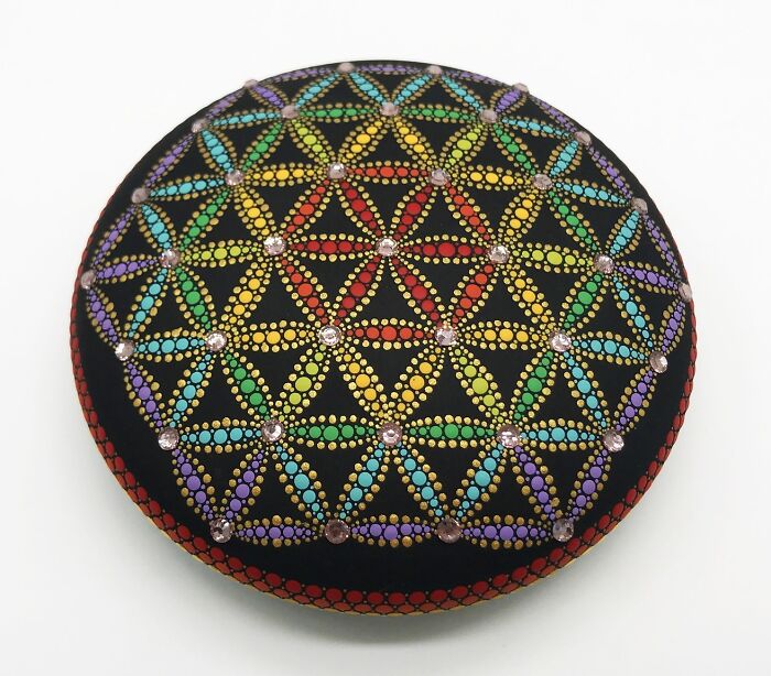 Colorful mandala art on a stone, featuring intricate geometric patterns.