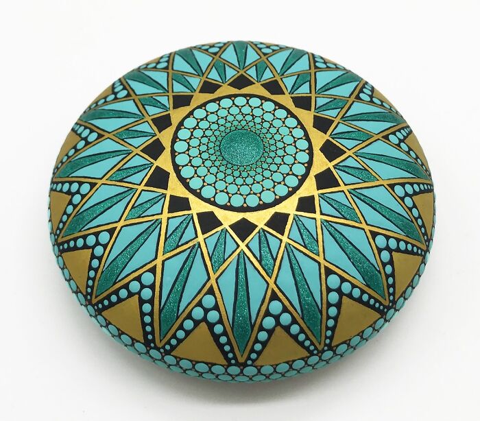 Beautiful mandalas painted on a smooth stone, showcasing intricate patterns and vibrant colors.