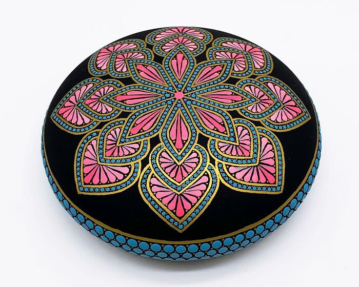 Beautiful mandala artwork painted on a smooth, round stone, showcasing intricate patterns and vibrant colors.
