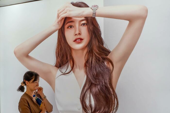 A woman stands aligned with a large poster, creating a perfectly timed optical illusion.