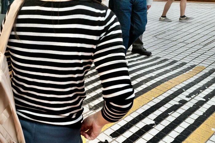 Person in a black and white striped shirt blending with a striped floor, creating a lucky coincidence effect.