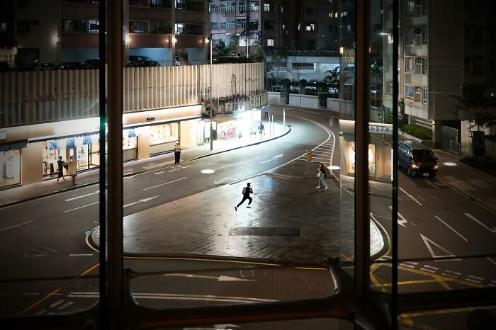 Night scene of a person running across a lit street, captured at a perfectly timed moment.
