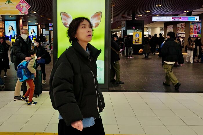 Person walking indoors, aligned with an ad behind them that shows animal ears, creating a perfectly timed coincidence.
