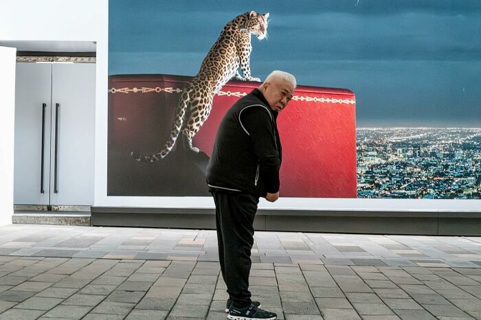 Man standing in front of a billboard, perfectly aligned with the image of a leopard, creating a lucky coincidence.