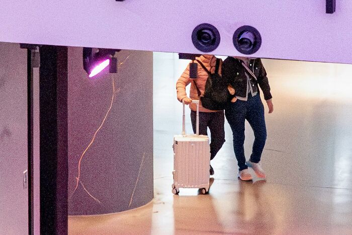 Two people perfectly aligned with a ceiling structure, creating a visual illusion in this lucky coincidence photo by Edas Wong.