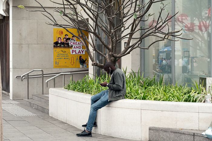 A man sits by a tree, with branches appearing as antlers, in this perfectly timed photo by Edas Wong.