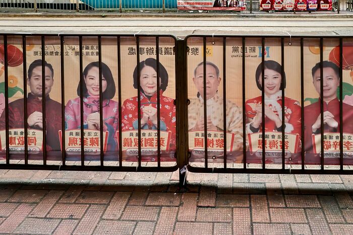 People on a poster appear behind a metal fence, creating a perfectly timed visual illusion.