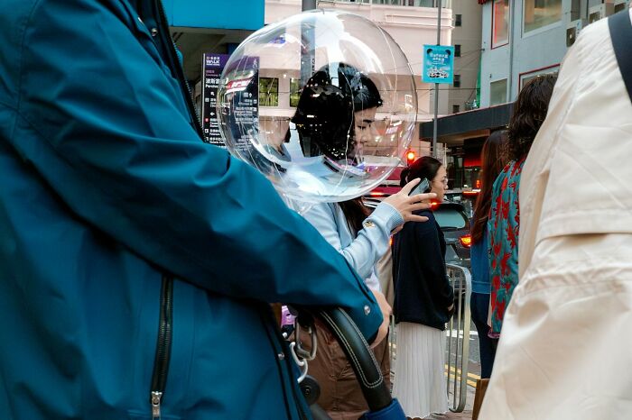 A perfectly timed photo by Edas Wong shows a person’s head aligned with a transparent balloon, creating a surreal effect.