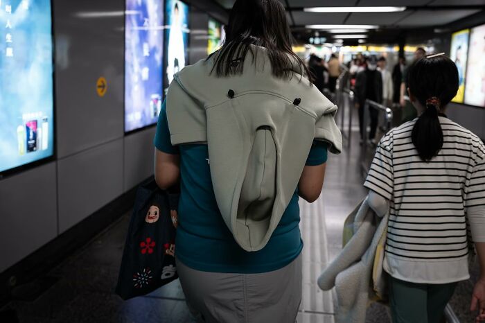 A perfectly timed photo captures a hoodie on a person's back, resembling a surprised face, in a subway walkway.